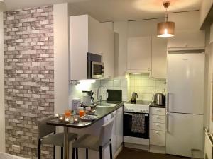 ロヴァニエミにあるカーサ アークティカ アパートメントの白いキャビネットとテーブル(ドリンク付)が備わるキッチン