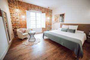 1 dormitorio con cama y pared de ladrillo en Hostal Albany Ancha en León