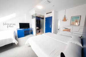 a white bedroom with a large bed and a tv at Hostal Albany in León