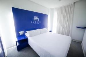 1 dormitorio con cama blanca y pared azul en Hostal Albany, en León