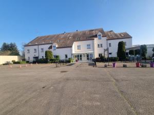 un grand bâtiment blanc avec un grand parking dans l'établissement Logis Hôtel Sully le Château, à Saint-Père-sur-Loire