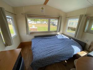 - un lit dans une petite chambre avec 2 fenêtres dans l'établissement Chalet Formentera in de duinen van IJmuiden aan Zee, à IJmuiden