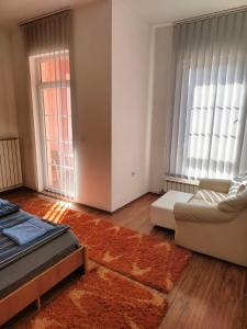 sala de estar con sofá, cama y ventanas en Apartman br 4, en Bijeljina