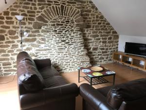 sala de estar con sofá de cuero y pared de ladrillo en Gite de Kermoel, île de Bréhat, en Kernascléden