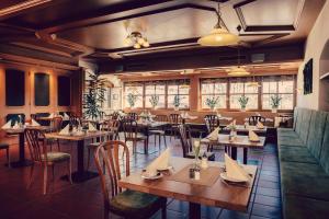 a restaurant with wooden tables and chairs and windows at Landhotel Hallnberg in Walpertskirchen
