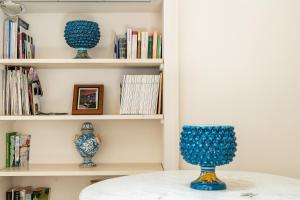 drei blaue Vasen auf einem Tisch in einem Bücherregal in der Unterkunft Blue Levante Vista Mare con terrazza in Syrakus