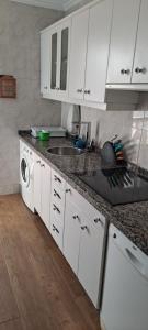 cocina con armarios blancos, fregadero y lavavajillas en Casa Camilo, en San Juan de la Arena