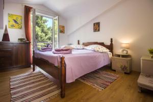 1 dormitorio con cama con sábanas rosas y ventana en House Kvin, en Baška Voda
