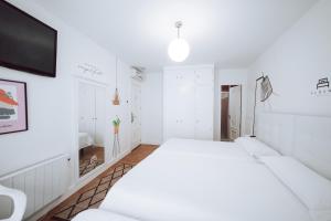 a white bedroom with a bed and a tv at Hostal Misericordia in León