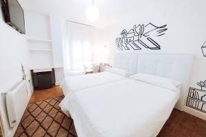 two beds in a room with white walls at Hostal Misericordia in León