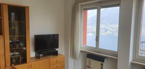 a living room with a tv and a window at La bella vista sul lago di Como in Valbrona