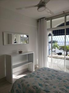 een witte slaapkamer met een bed en een spiegel bij Indy's Best Bay FrontView in Samana. in Santa Bárbara de Samaná