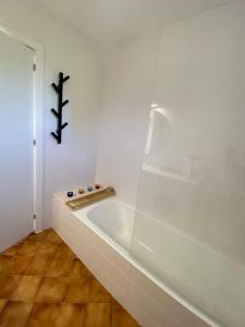 Un baño blanco con bañera y una cruz en la pared. en Apartamento Las Camelias 13, en Son Bou 7 fotos más