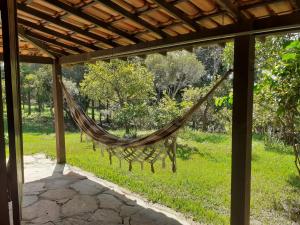 a hammock hanging from a pergola in a yard at Chalés paradise - Família in Serra do Cipo +14 photos