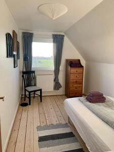 1 dormitorio con 1 cama, 1 silla y 1 ventana en Jægergård, en Skærbæk
