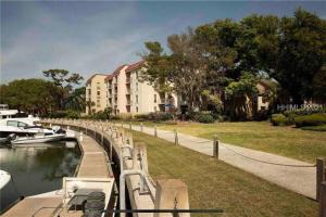 a boat is docked in a canal next to a building at In the Heart of Harbour Town 2BR 2BA Pool Access Close to Beach in Hilton Head Island