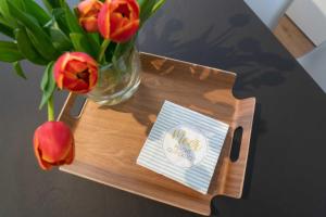 una pequeña bandeja de madera con un jarrón de flores y una nota en Meerkieker, en Norderney