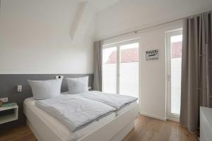 1 dormitorio blanco con 1 cama grande y ventanas en Meerkieker, en Norderney