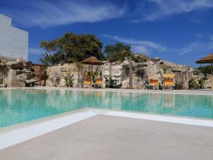 a pool at a resort with chairs and umbrellas at L'Oasi Villaggio Albergo in Favignana