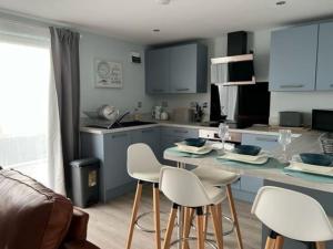 a kitchen with white chairs and a counter with a table at Orchard Lodge -Coastal Retreat, new build, village views, private garden and terrace in Saint Brides Major