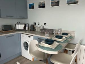 a kitchen with a table and a dishwasher at Orchard Lodge -Coastal Retreat, new build, village views, private garden and terrace in Saint Brides Major