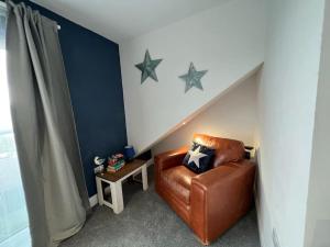 a brown leather chair in a room with stars on the wall at Orchard Lodge -Coastal Retreat, new build, village views, private garden and terrace in Saint Brides Major