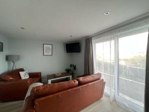 a living room with a couch and a large window at Orchard Lodge -Coastal Retreat, new build, village views, private garden and terrace in Saint Brides Major