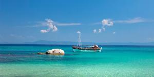 a boat sitting in the water next to a rock at Anna house 1 in Sarti