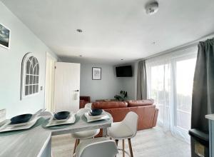 sala de estar con sofá, mesa y sillas en Orchard Lodge -Coastal Retreat, new build, village views, private garden and terrace en Saint Brides Major