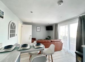 a living room with a couch and a table and chairs at Orchard Lodge -Coastal Retreat, new build, village views, private garden and terrace in Saint Brides Major