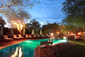 a swimming pool with chairs and umbrellas at night at Grand Kruger Lodge and Spa in Marloth Park