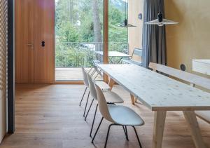 a dining room with a table and white chairs at Älmele - Waldchalets Brandnertal in Brand