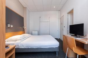 a bedroom with a bed and a desk with a television at Modern Waikiki Hotel in Cannes