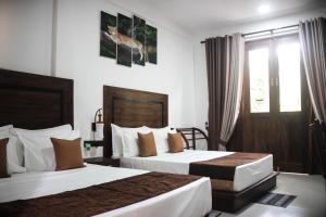 a hotel room with two beds and a window at Divine Villa in Anuradhapura