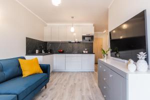 salon z niebieską kanapą i kuchnią w obiekcie Apartament Baltic Sun N°37 w Sztutowie