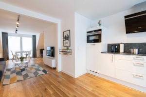 a kitchen and living room with white cabinets and a table at LightHouse Whg 5 in Norderney