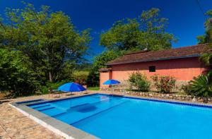 a swimming pool with two umbrellas next to a building at Pousada Casa de Pedra in Iporanga