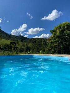 a large pool of blue water with trees in the background at Chácara Bertelli in Socorro