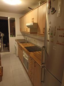 a kitchen with wooden cabinets and a stainless steel refrigerator at Cozy Room with sunny terrace in Marbella