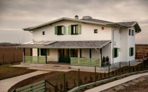 une maison blanche avec volets verts sur un champ dans l'établissement Pensiunea Floarea Soarelui, Piscu, à Piscu