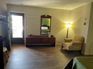 a room with a bed and a mirror and a chair at Gas Lite Motel Lawrenceville in Lawrenceville