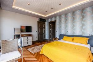 a bedroom with a yellow bed and a tv at ORIGINE RENTALS AN2 in Hurmaköy +23 photos