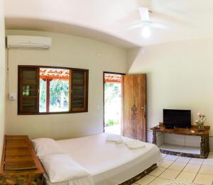 a bedroom with a large white bed and a desk at Pousada Casa de Pedra in Iporanga