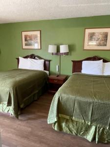 um quarto de hotel com duas camas e paredes verdes em Gas Lite Motel Lawrenceville em Lawrenceville