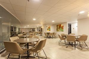 a cafeteria with tables and chairs in a building at Travel Inn Axten Caxias do Sul in Caxias do Sul