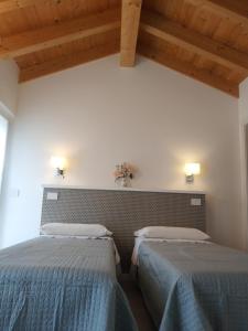 two twin beds in a room with wooden ceilings at sweet homes in Lecco