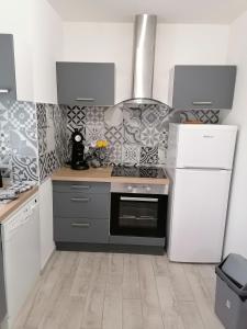Il comprend une cuisine équipée d'une cuisinière et d'un réfrigérateur blanc. dans l'établissement La forge, à Saint-Palais-sur-Mer