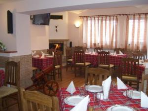 a dining room with tables and chairs and a fireplace at Kashta Peychevi in Govedartsi