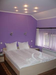 ein Schlafzimmer mit einem großen weißen Bett mit einer lila Wand in der Unterkunft Kashta Peychevi in Govedartsi