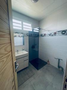 een badkamer met een douche en een wastafel bij Charmant appartement coloré proche de la plage in Bouillante
